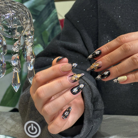 Close-up of the intricate floral artwork on the glossy black press on nails.