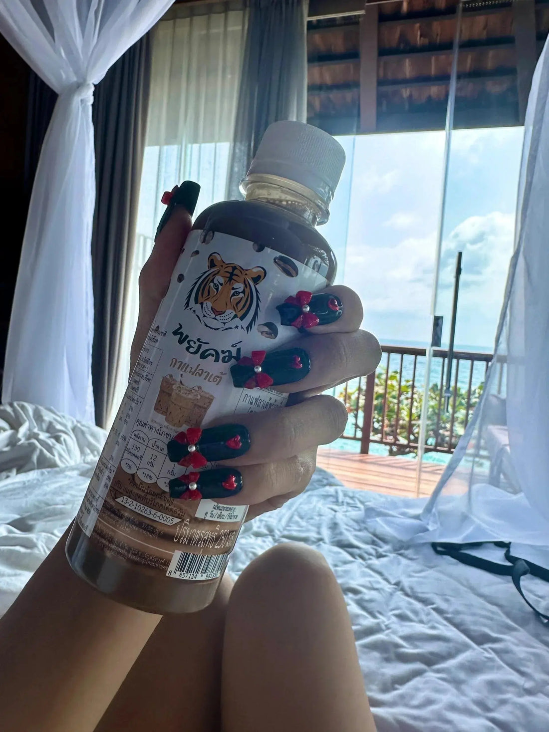 Hand with Tsuki Nails press on manicure holding a tiger drink bottle in a sunny bedroom