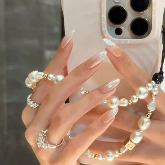 Salon-quality press on nails with glossy nude finish, holding a phone with pearl accessories