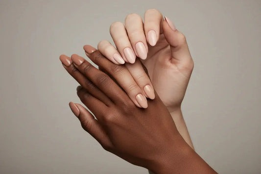 Three hands with different skin tones wearing Tsuki Nails nude press on manicure against a neutral background.