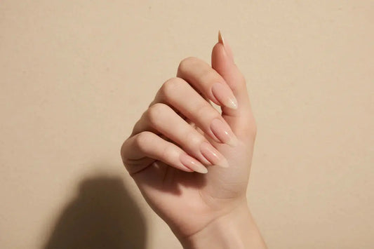 Almond-shaped nude press on nails with high gloss finish by Tsuki Nails, beige background