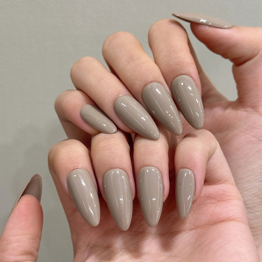 Grey Muse press on nails full set, warm taupe matte finish in a sharp stiletto shape.

