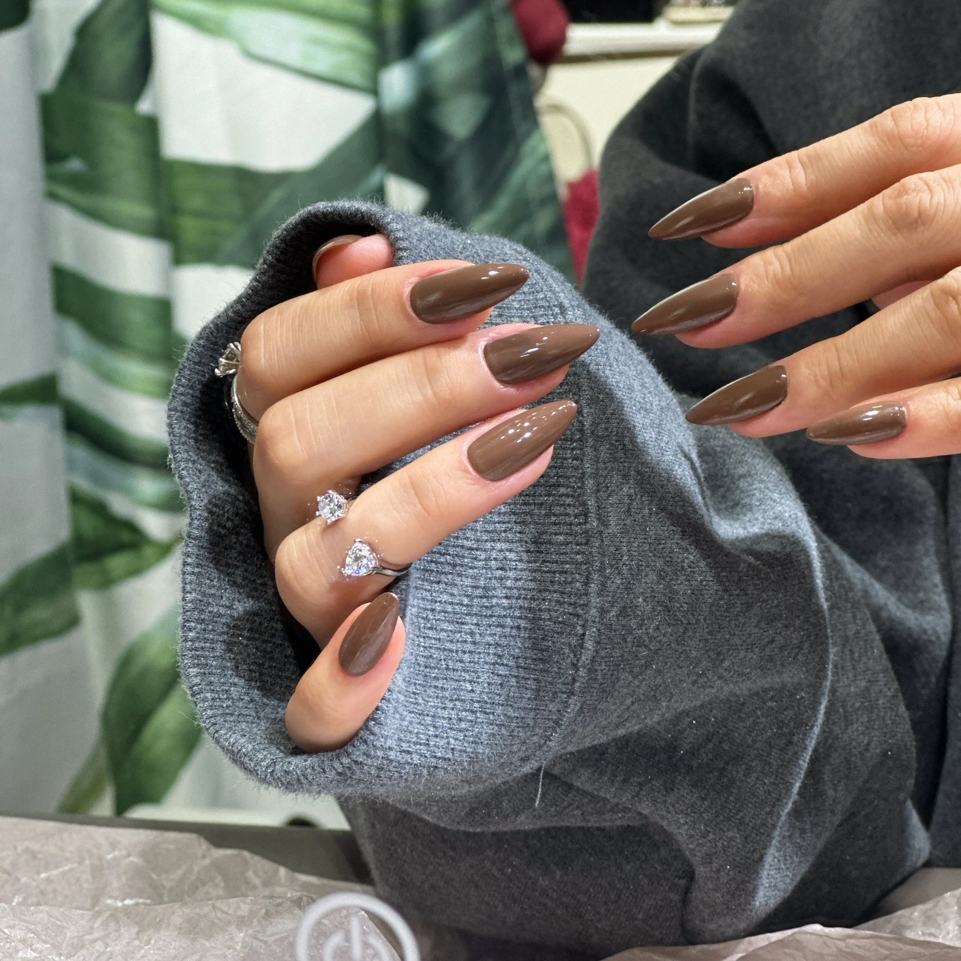 Close-up of the deep brown glossy finish on stiletto nails.
