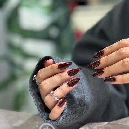 Close-up of the rich burgundy color and glossy finish on the stiletto press on nails.

