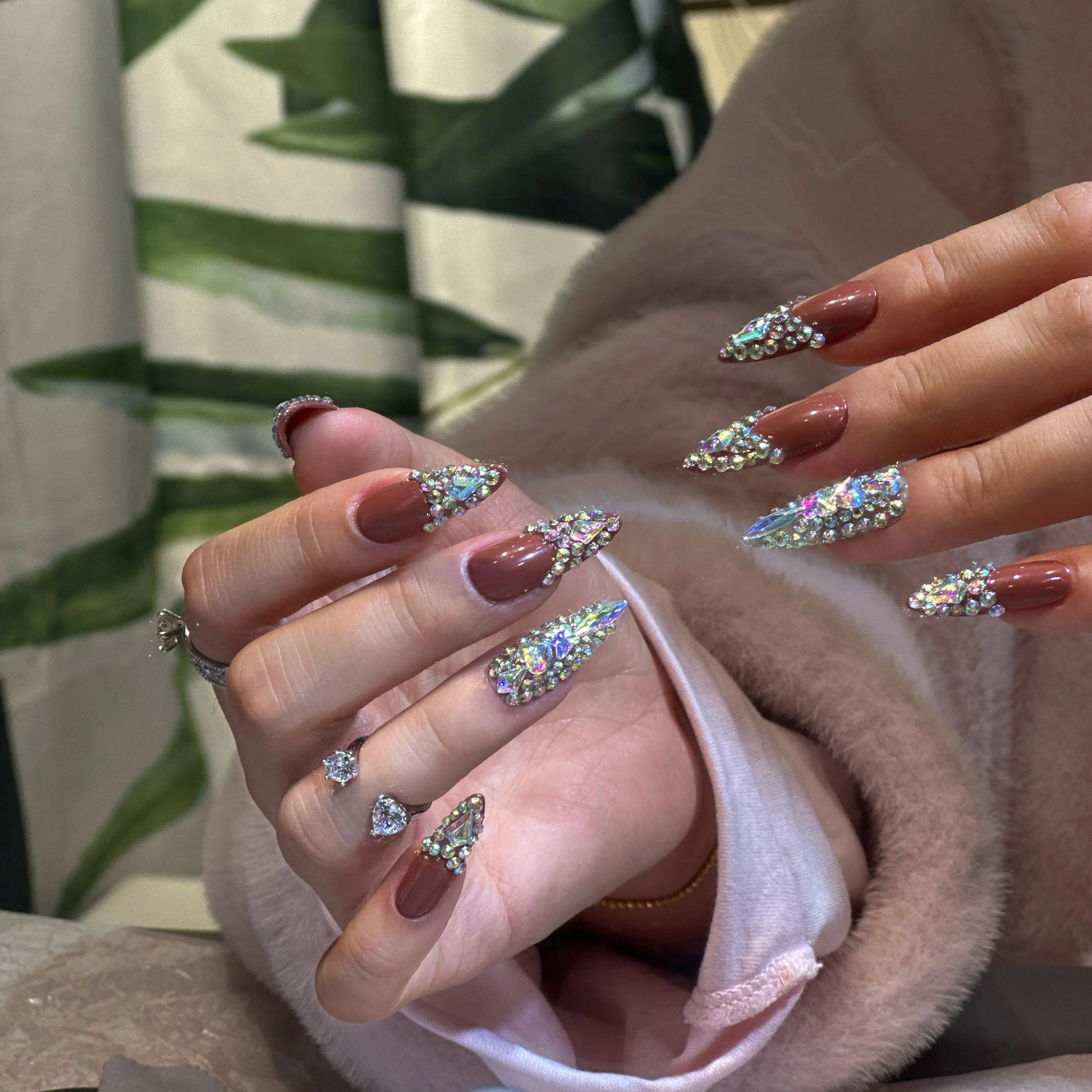 Rich terracotta brown color and glossy finish on the crystal-embellished nails.

