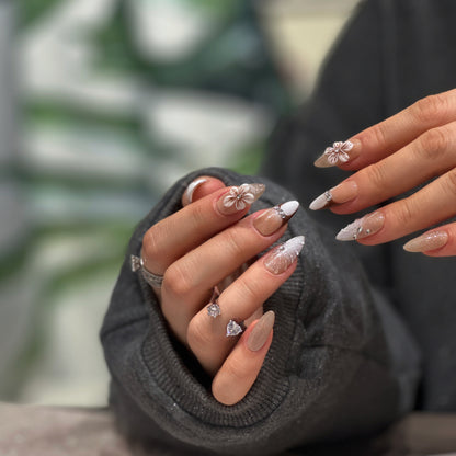 Close up of elegant almond press on nails with brown french tips and 3D white flower charms

