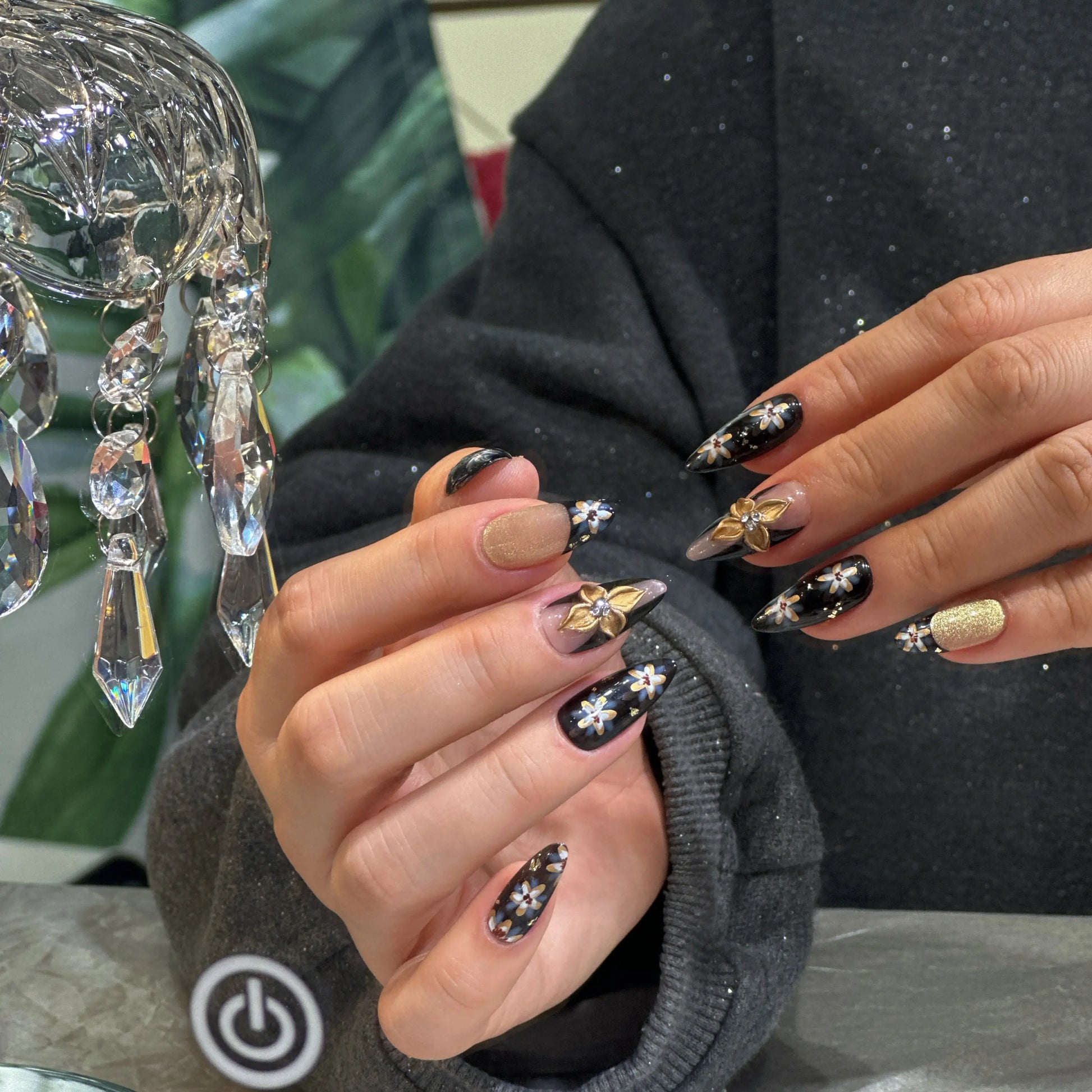 Close-up of the intricate floral artwork on the glossy black press on nails.