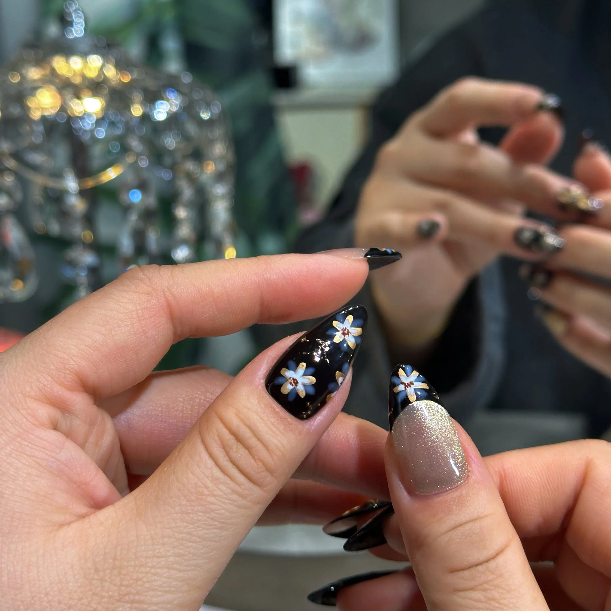 Elegant manicure with Raven Blossom black floral press on nails worn on hand.