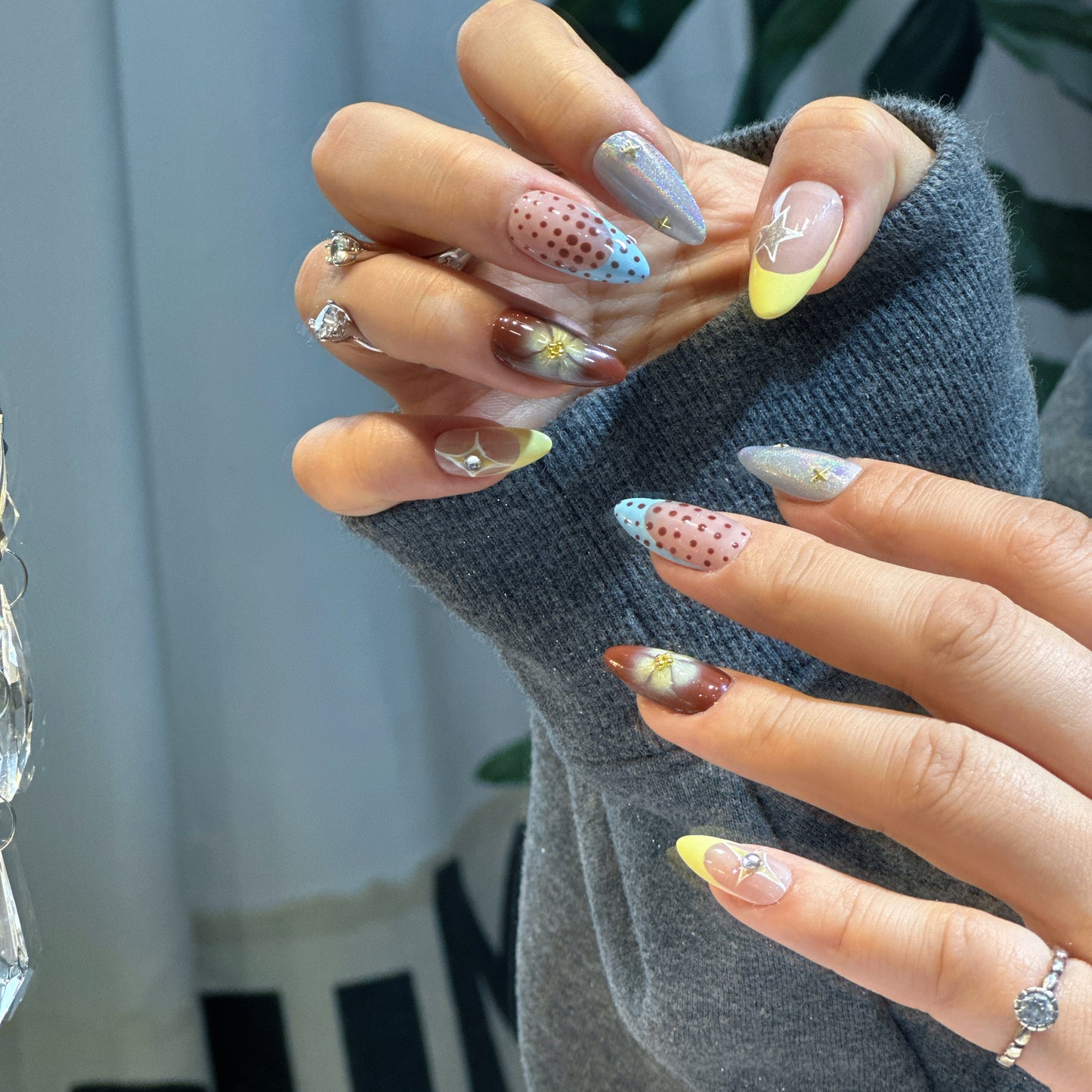 Hand modeling Starry Dots nails displaying burgundy ombre, pink-blue polka dots and 3D white flowers

