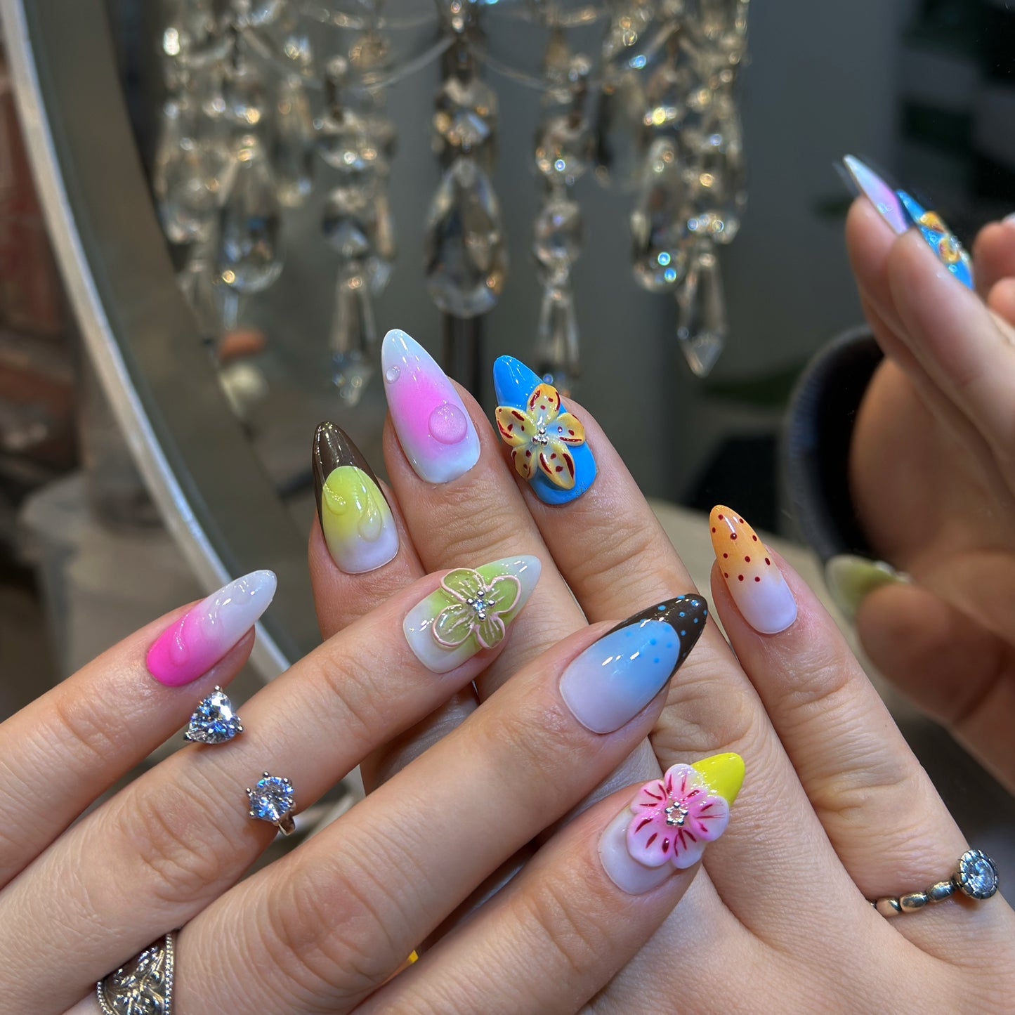 Hand modeling Rainbow Garden nails displaying vibrant rainbow gradients with pink, blue, yellow, green and purple ombre
