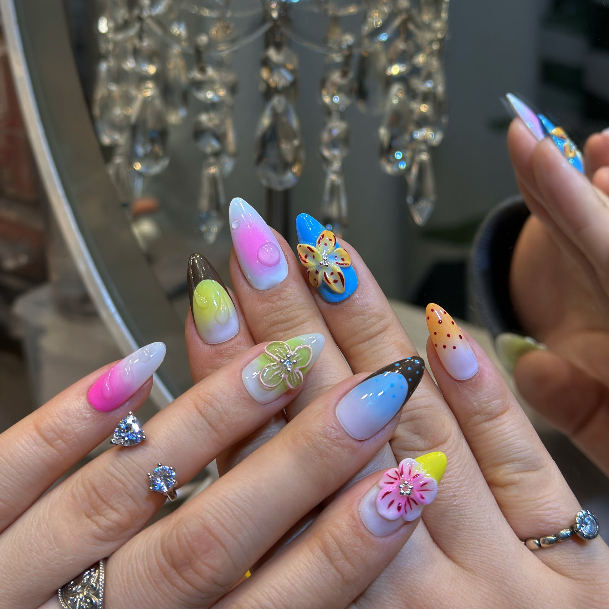 Hand modeling Rainbow Garden nails displaying vibrant rainbow gradients with pink, blue, yellow, green and purple ombre
