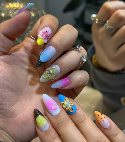 Both hands wearing Rainbow Garden nails with colorful polka dots, floral accents and sparkling rhinestone embellishments
