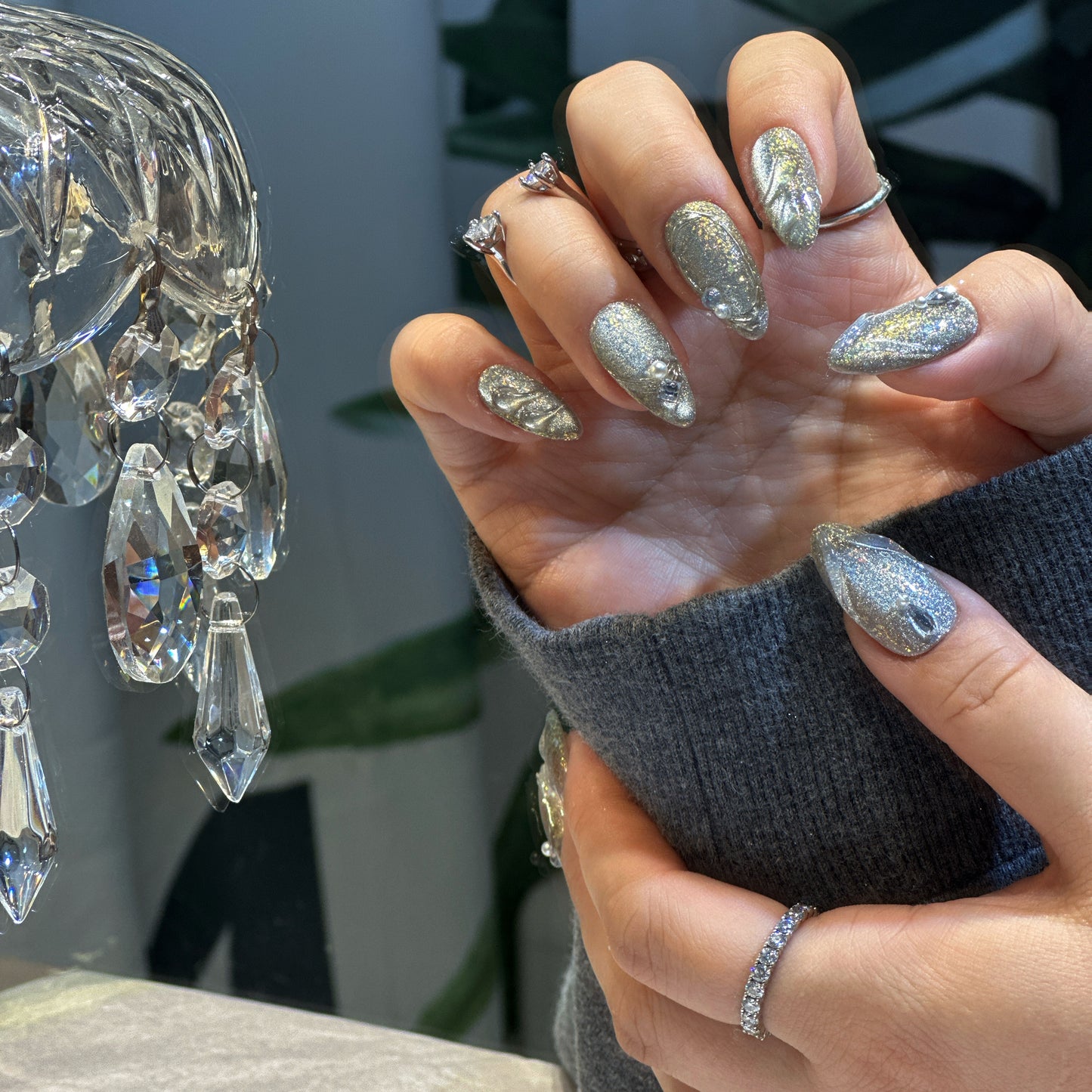 Close-up of Silver Feather press-on nails showing graceful leaf patterns with sparkling crystal rhinestone embellishments
