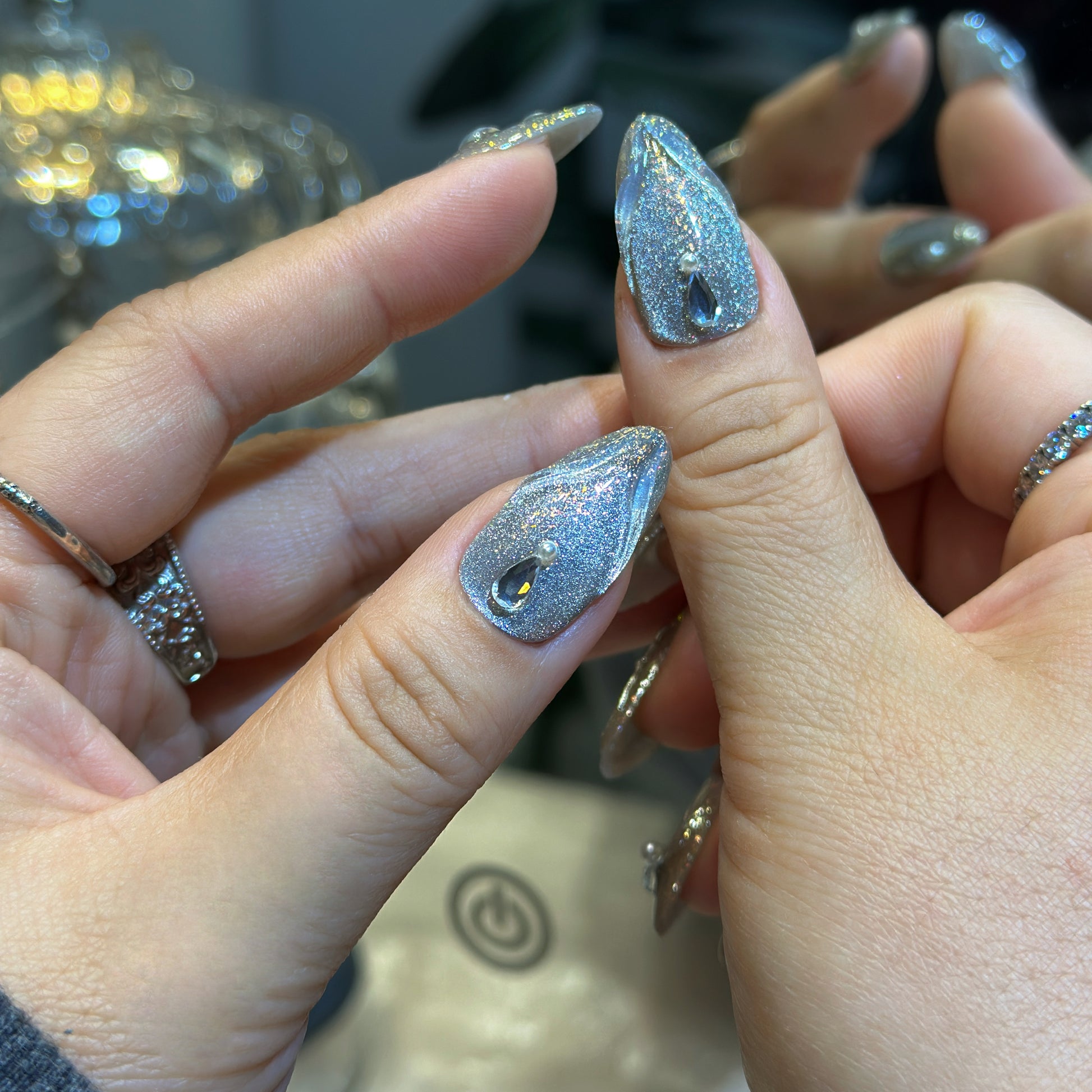 Side angle of Silver Feather nails with lustrous pearl accents and ethereal silver shimmer finish
