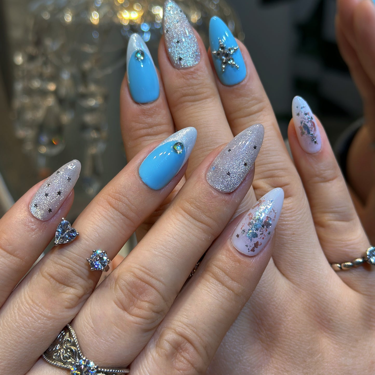 Hand modeling Celestial Cross nails displaying sparkling crystal cross decorations with black star patterns and silver sequins
