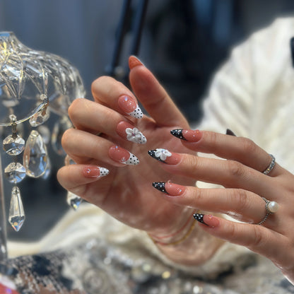 Close-up of Polka Dot Bloom press-on nails displaying 3D white flowers with pink-purple centers and iridescent crystal accents
