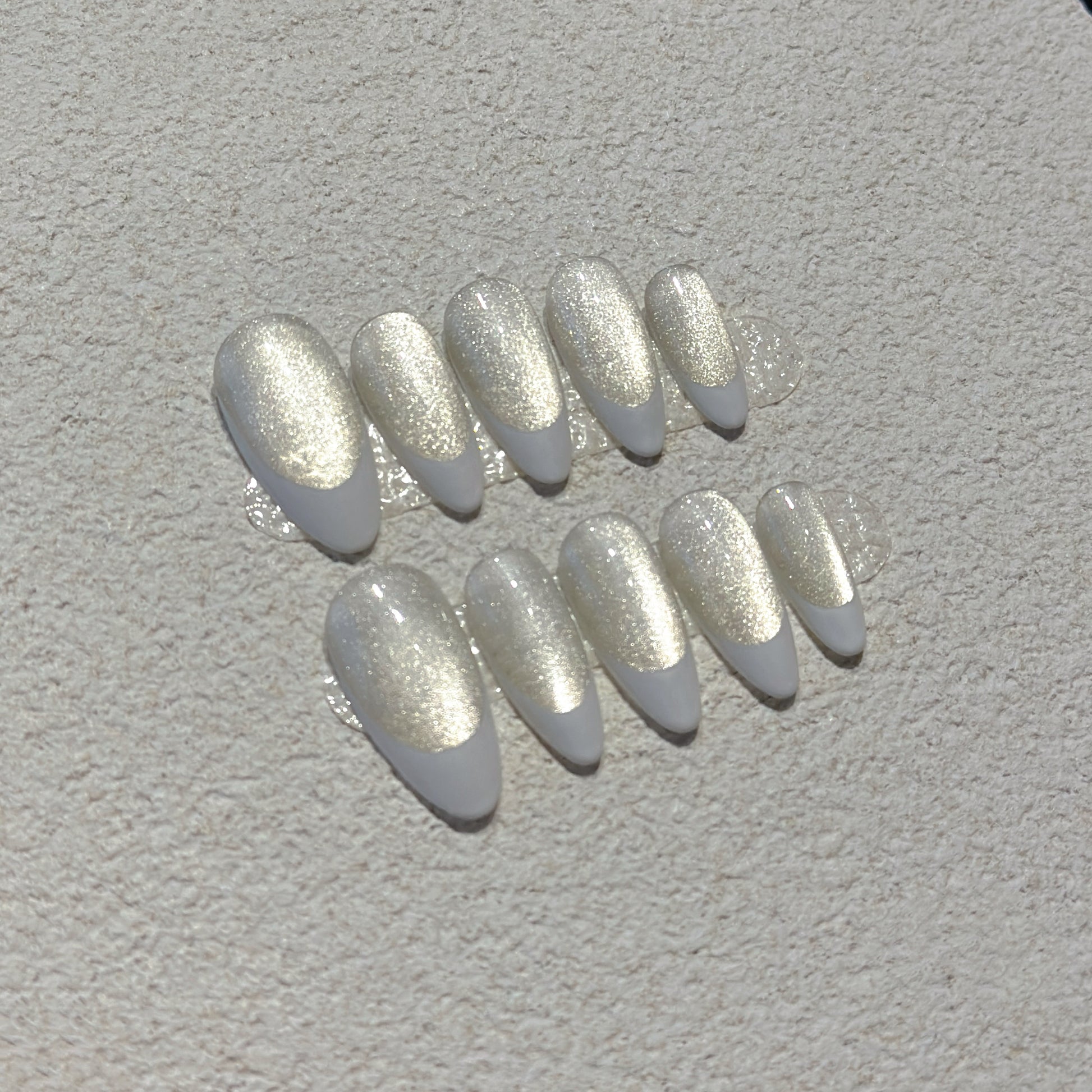 Pearl French Shimmer press-on nails showing milky nude base with crisp white French tips and champagne silver shimmer
