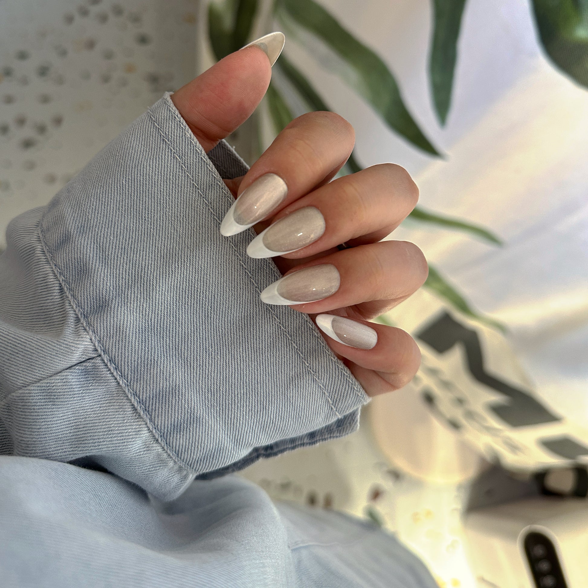 Hand wearing Pearl French Shimmer press-on nails in natural light showing clean white French tips and milky nude base
