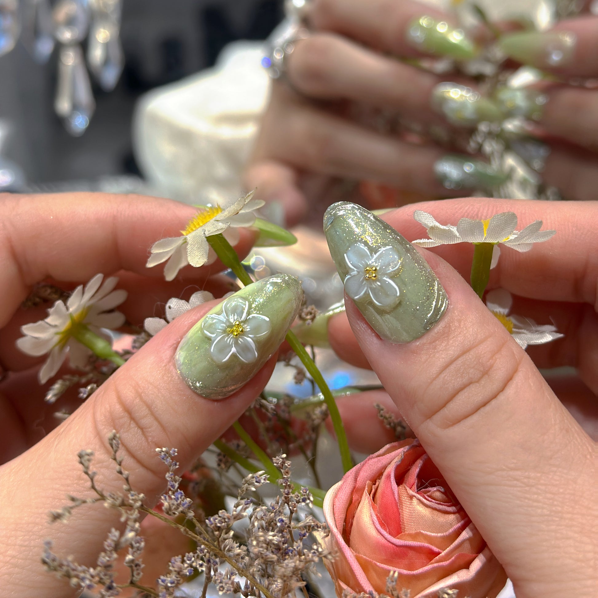 Close-up of Matcha Daisy Garden nails showing alternating matcha green glitter and sheer opal base with pearl embellishments
