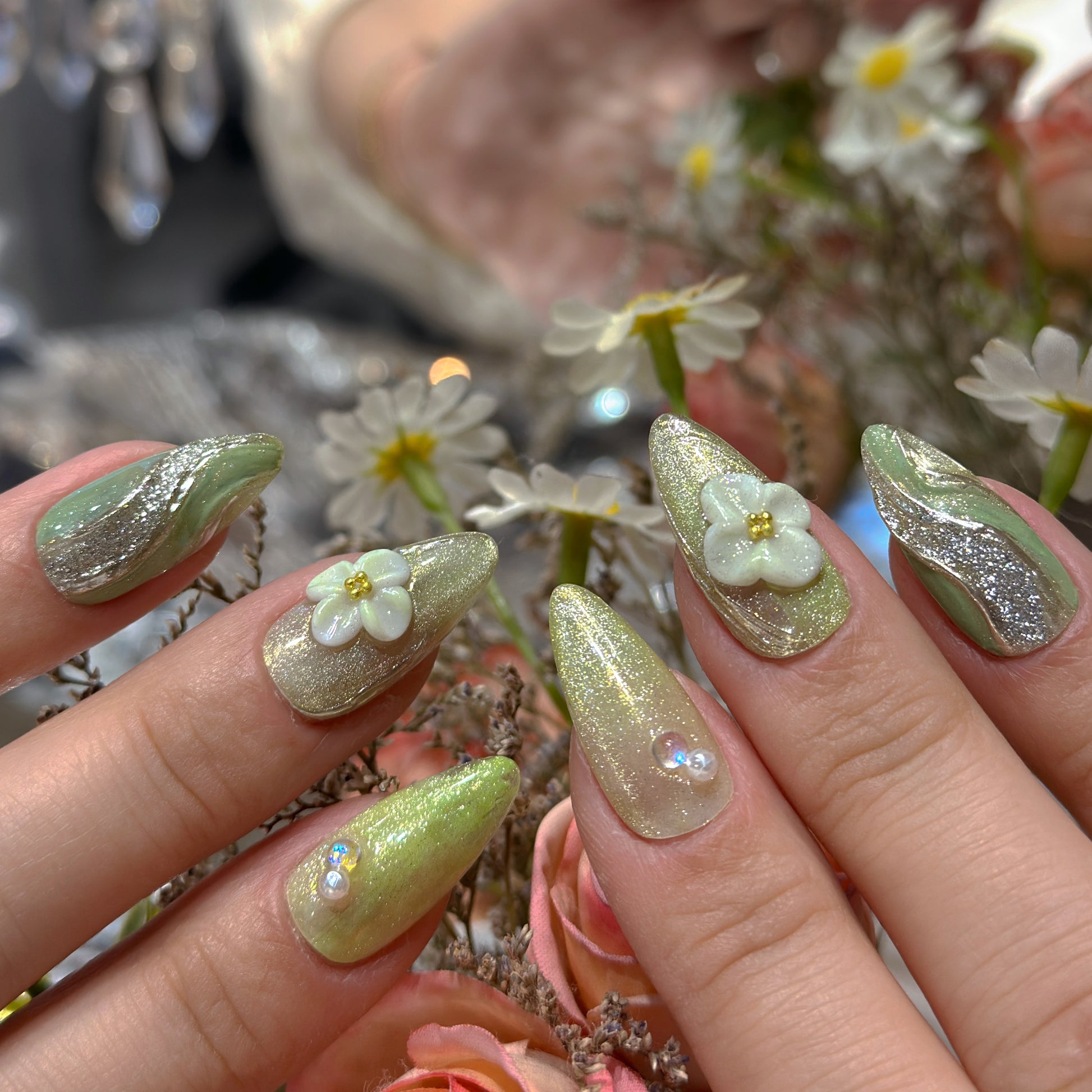 Side angle of Matcha Daisy Garden press-on nails with green marble swirls and 3D daisy flowers in stiletto shape
