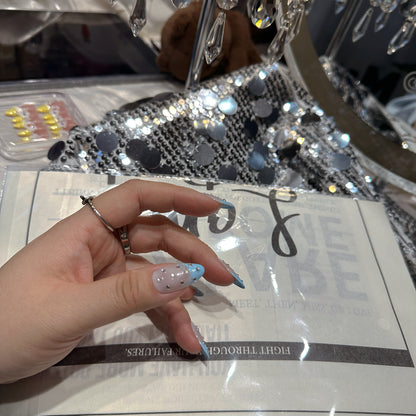 Single hand wearing Blue French Crystal Rain press-on nails with crystal chandelier showing almond shape and blue French tip detail
